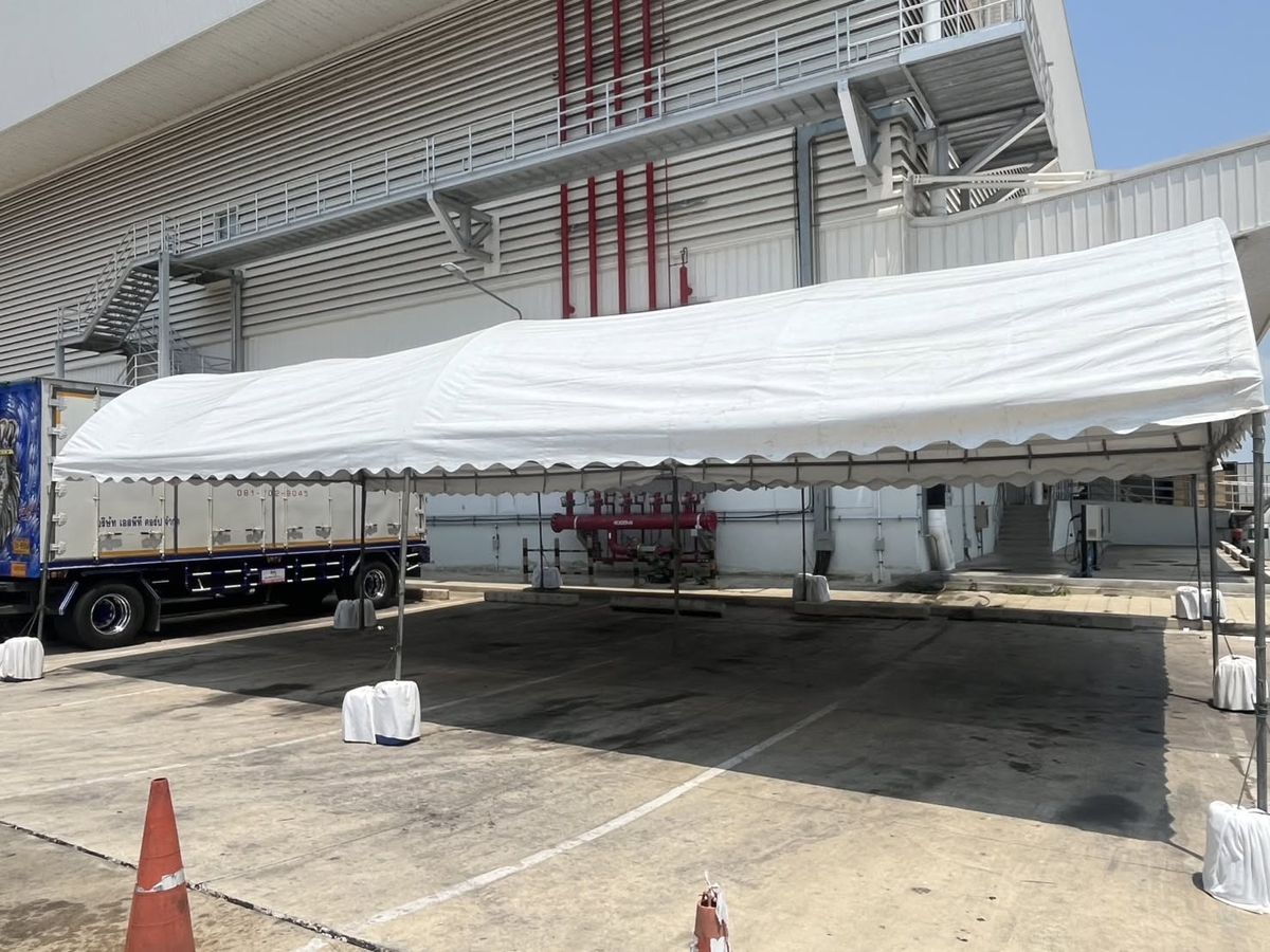 เต็นท์คลุมลานขนถ่ายสินค้าหน้าโรงงาน มีรถบรรทุกจอดข้าง